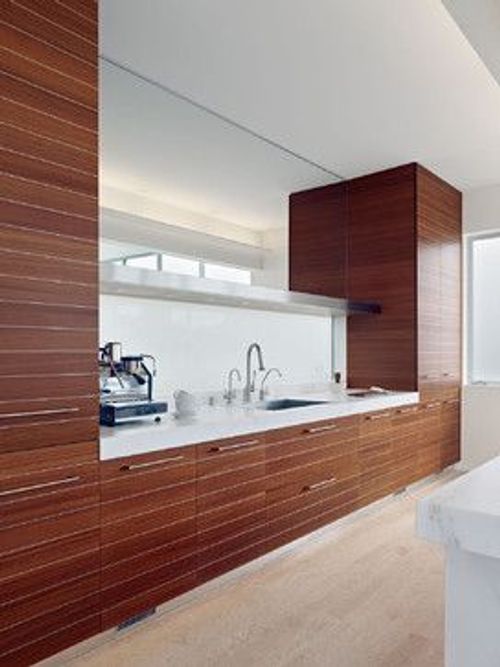 a modern kitchen with wooden cabinets and white counter tops, along with an island in the middle