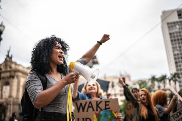 young woman leading a demonstration using a megaphone - revolt revolution stock pictures, royalty-free photos & images