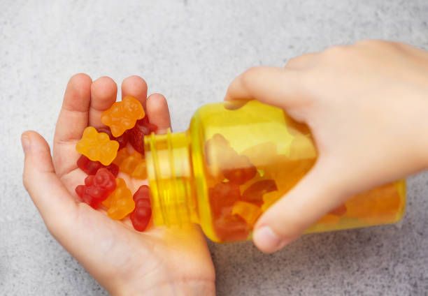 A girl holds a gummy bear vitamines in her hands Chewable gummy bears vitamins and supplements.  A girl holds a gummy bear vitamines in her hands. red gummies stock pictures, royalty-free photos & images