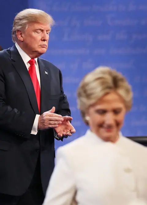 Getty Images Hillary Clinton walks off stage as Donald Trump applauds during a debate.