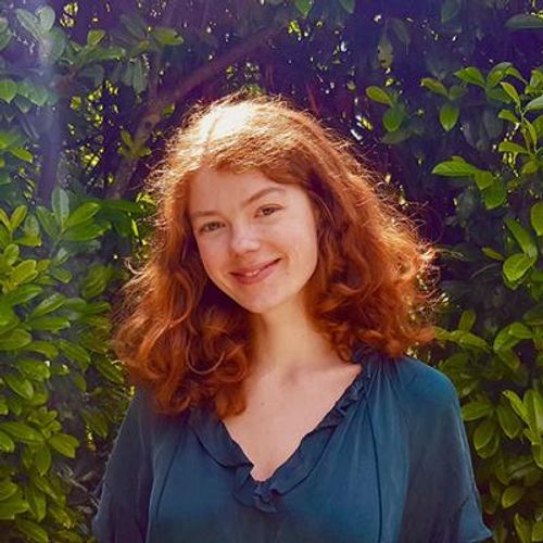 Emily Jones in a green top, smiling in front of a leafy background