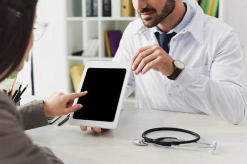 cropped image of doctor showing patient tablet with blank screen in clinic - Photo, Image