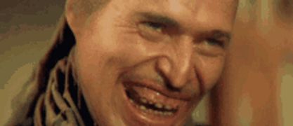 a close up of a man 's face with a scarf around his neck making a funny face