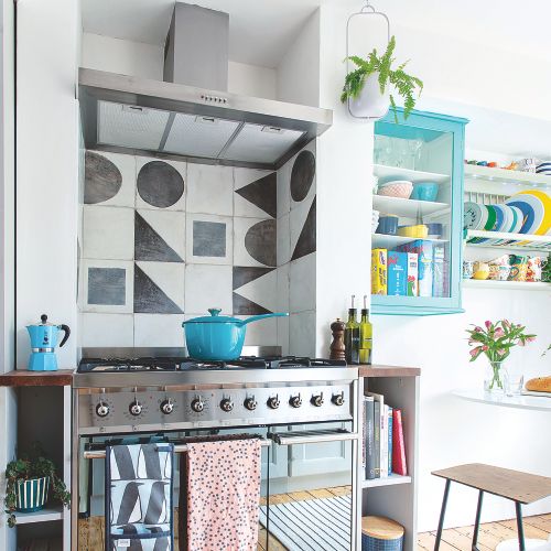 Kitchen with black and white geometric tiles and stainless steel stove.