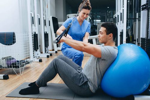 kinesiologist helps a mixed race man doing exercises to strengthen his back muscles. treatment of back pain using kinesitherapy. kinesiologist helps a mixed race man doing exercises to strengthen his back muscles. treatment of back pain using kinesitherapy. kinesiologist stock pictures, royalty-free photos & images