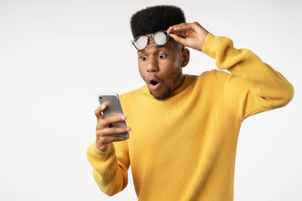 Shocked african man while watching in smartphone on isolated white background Background, African Ethnicity, People, Males, Copy Space flabbergasted stock pictures, royalty-free photos & images
