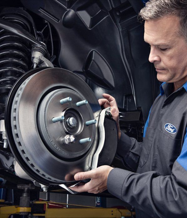 Ford technician performing brake service and inspecting brake rotor at Irvine Ford