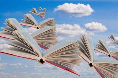 Livres volent sur le fond du ciel nuageux