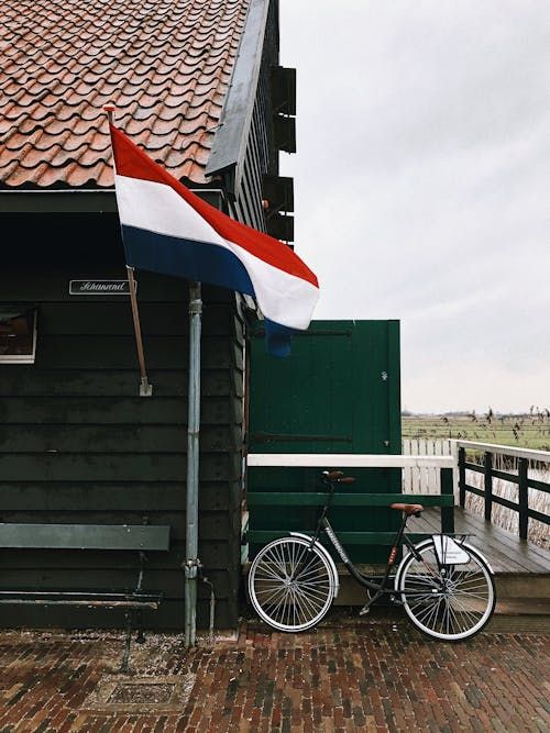 Free A classic Dutch scene featuring a bicycle and flag by a traditional Zaandam wooden house. Stock Photo