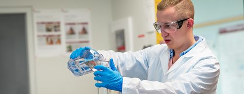 male student in laboratory pouring liquid