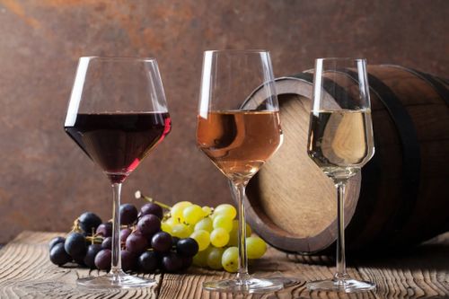 Wine colour chart illustration with three glasses of red, rosé, and white wine showing different shades alongside grapes and a wine barrel.