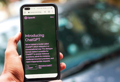 Free Close-up of a smartphone showing ChatGPT details on the OpenAI website, held by a person. Stock Photo