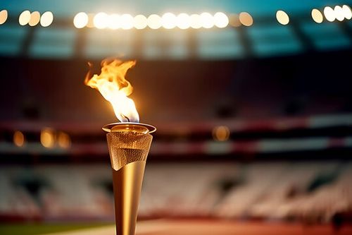 Flame burns in Olympic torch against blurred sports arena