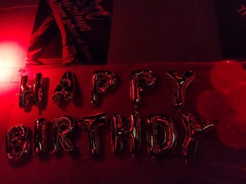 Free Red-lit balloon display spelling 'Happy Birthday' with celebratory atmosphere. Stock Photo