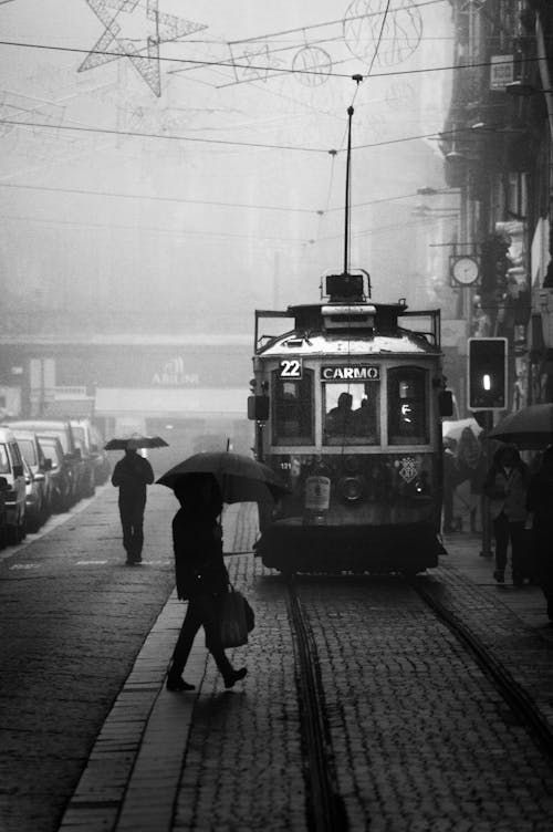 Free A black and white photo of a tram in Porto, capturing rainy street life and public transportation. Stock Photo