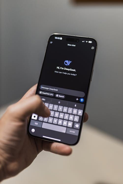 Free Close-up of a smartphone with an AI chat interface titled "DeepSeek" on the screen. Stock Photo