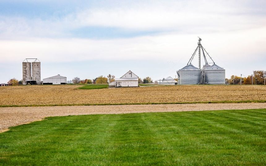 Farm landscape with white barn and metal grain bins, bought with an agricultural loan from Farm Credit Mid-America.