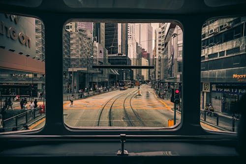Free A bustling Hong Kong street seen through a tram window, featuring skyscrapers and public transport. Stock Photo