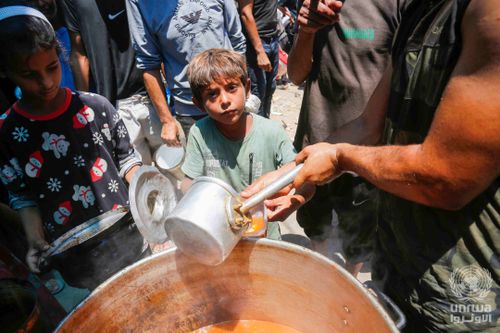 displaced palestinians gather to receive food from a charity in deir el balah gaza strip