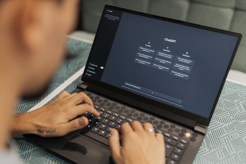 Free Close-up of a person typing on a laptop displaying the ChatGPT interface, emphasizing modern technology use. Stock Photo