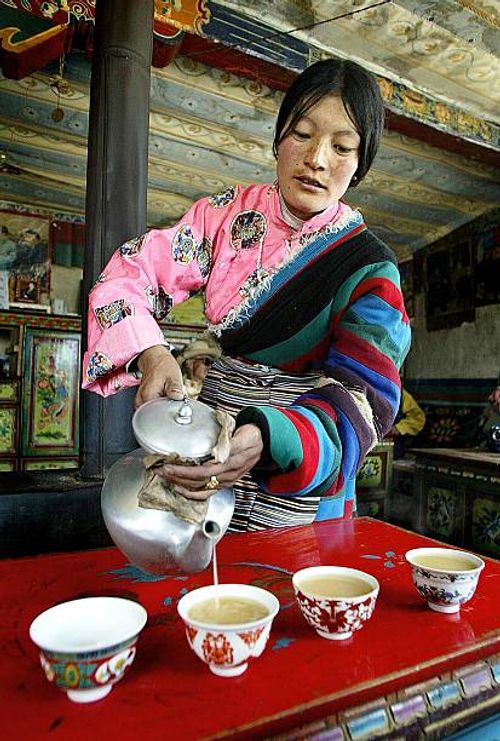 Woman serving yak butter tea in her Naqun home