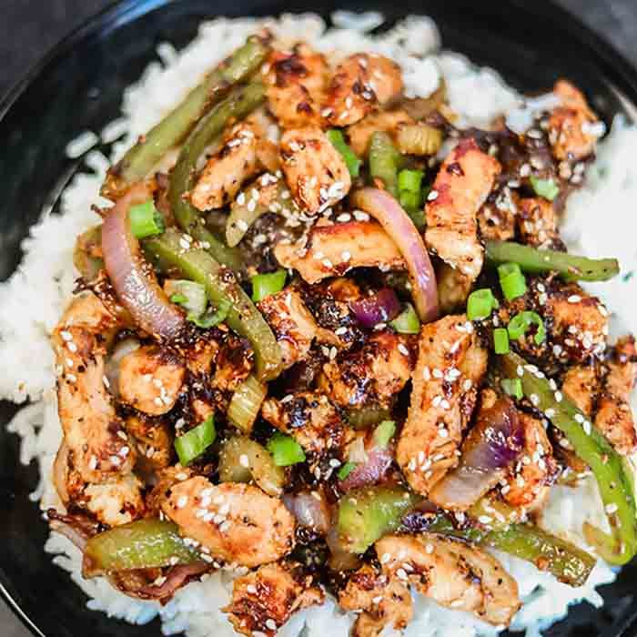 Close up image of black pepper chicken on rice.