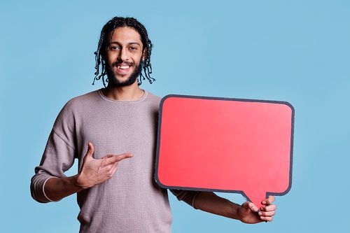 在蓝色背景下，微笑着的男人拿着空白的演讲泡泡的肖像图片下载