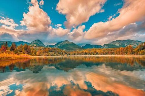 Autumn sunset landscape with tranquil peaceful mountain lake. Calmness nature in fall season. Foggy lake sunrise with autumn foliage and mountains, amazing clouds sky. Fantasy nature foliage photo