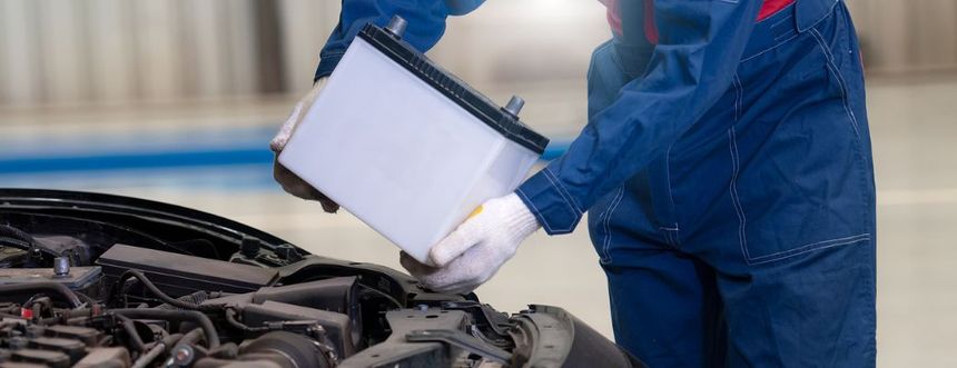 Automotive technician installing car battery during battery replacement service at Irvine Ford