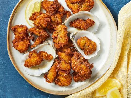 looking down at a plate of deep fried oysters with a lemon wedge garnish.
