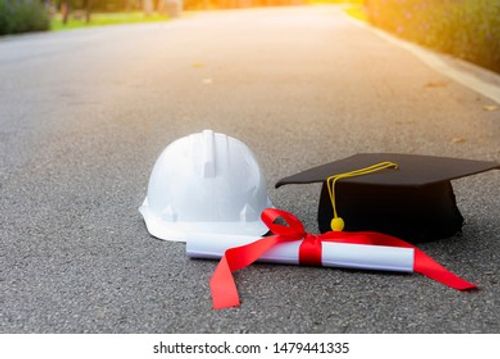 Certificate of graduation cap and helmet for engineers working on the road with green trees in the background Stock Photo