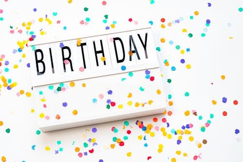 Free A vibrant birthday celebration background with colorful confetti and a birthday sign. Stock Photo