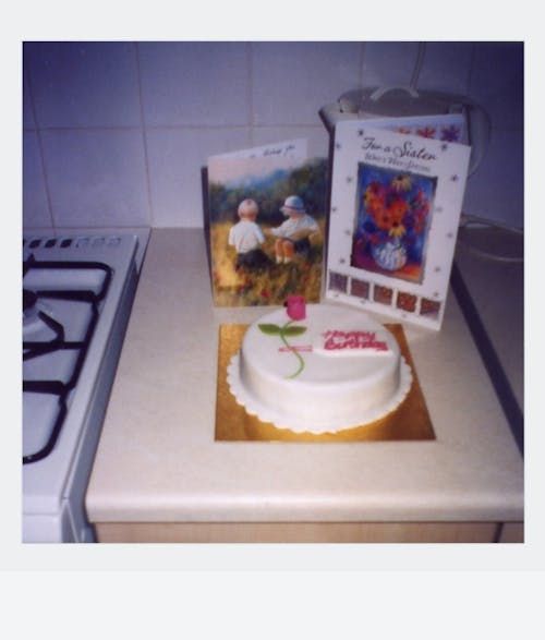 Free A vintage-style birthday cake with greeting cards on a kitchen counter, invoking nostalgia. Stock Photo