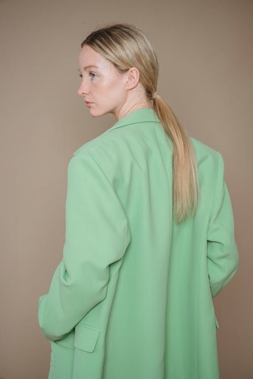 Free Elegant portrait of a woman in a fashionable green suit with a minimalist backdrop. Stock Photo