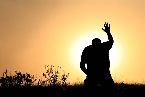 silhouette of man in praise and worship - religion stock pictures, royalty-free photos & images