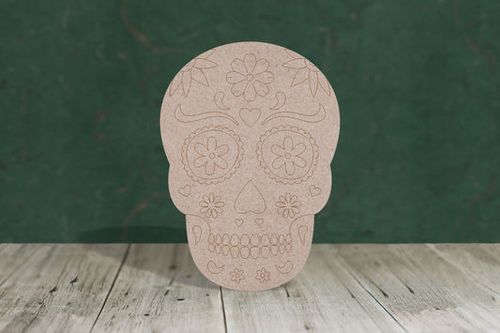 Decorative skull with floral patterns on a wooden surface with a green chalkboard background
