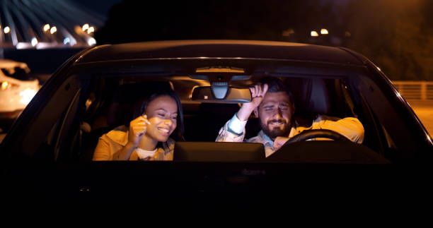 Couple enjoying a nighttime car drive with music and ambient lighting inside the vehicle