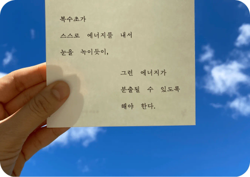 An image of a Lens shopping use case featuring a hand holding a Korean poem on a piece of paper against a blue sky.