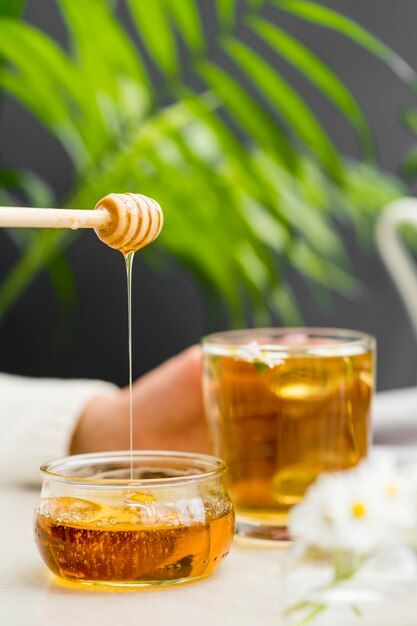 Free photo front view woman holding glass with tea and honey dipper