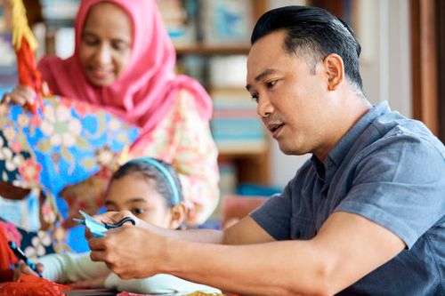 man cutting paper while making wau bulan at home - wau malaysia stock pictures, royalty-free photos & images