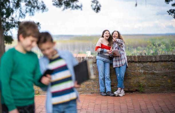las adolescentes señalan con el dedo a los niños en el parque y se ríen - presion social fotografías e imágenes de stock