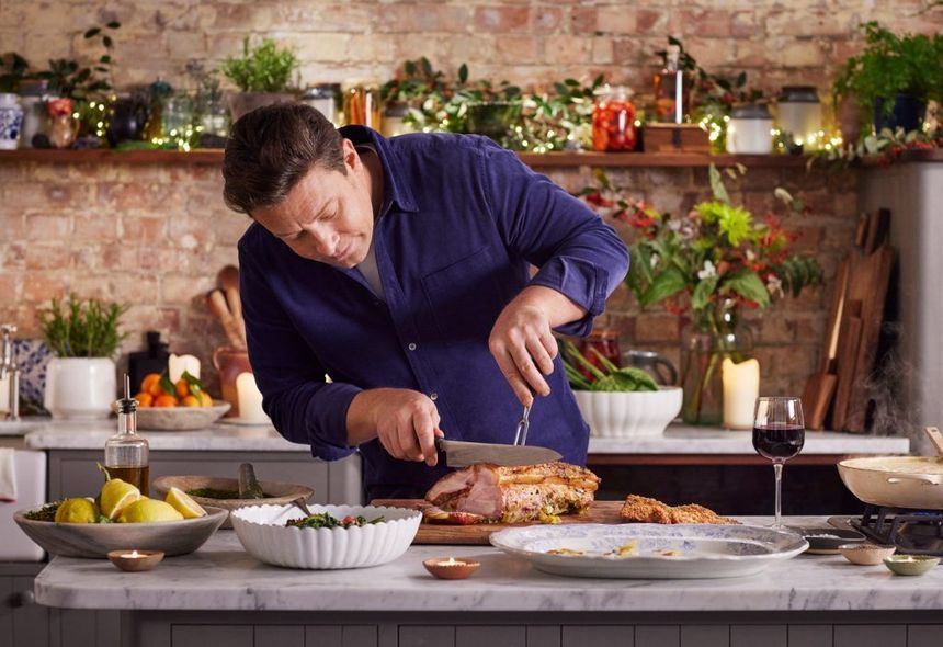 Jamie Oliver Knife Set carving a roast pork for New Year's Eve dinner with festive decorations for the occasion