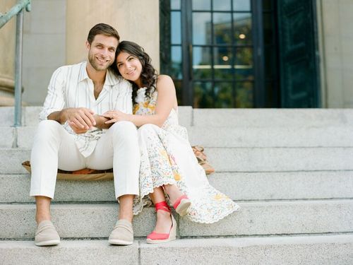 Cute Couple Poses: Couple poses for the camera while sitting on steps.