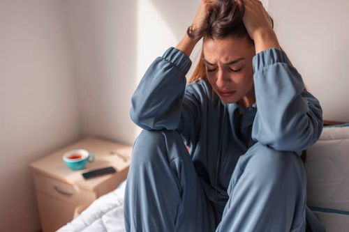Mulher ansiosa chorando na cama Mulher jovem ansiosa vestindo pijama, sentada na cama de manhã, segurando a cabeça entre as mãos, chorando estresse emocional fotos de stock, fotos e imagens livres de direitos autorais