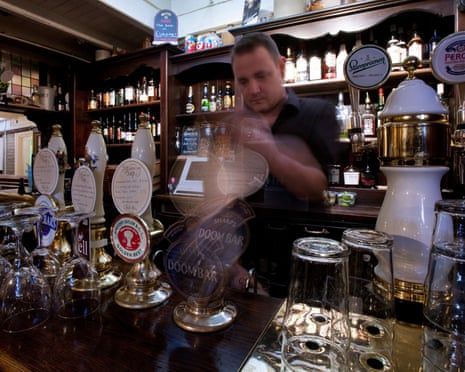 A barman pouring a draught beer behind a bar