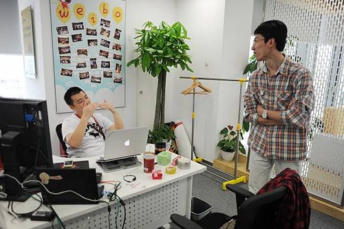 Staff members chat in an office of Sina Weibo, widely known as China's version of Twitter, in Beijing on April 16. Sina Weibo is set to go public in...