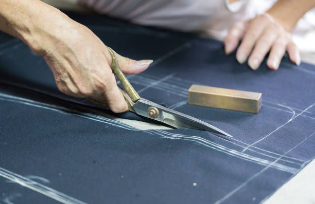 A tailor measuring fabric against a paper pattern
