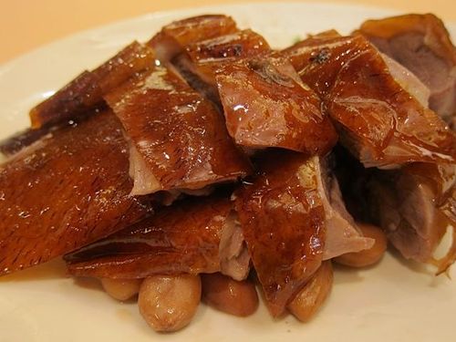 Diners enjoying roast duck in a bustling Sham Shui Po eatery