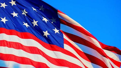 The American flag is shown against a blue sky background.