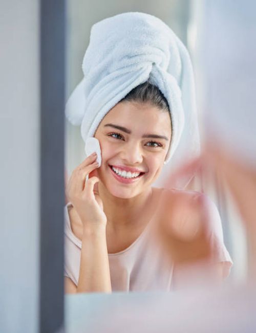 She enjoys looking after her skin Cropped shot of a beautiful young woman exfoliating her skin in the bathroom at home she stock pictures, royalty-free photos & images